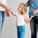 A child holding both parents’ hands, showing how the difference between parenting time and custody matters in real life.
